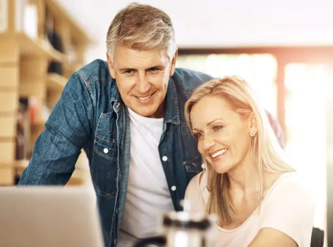 Couple reviewing monthly budget and retirement savings on laptop.
